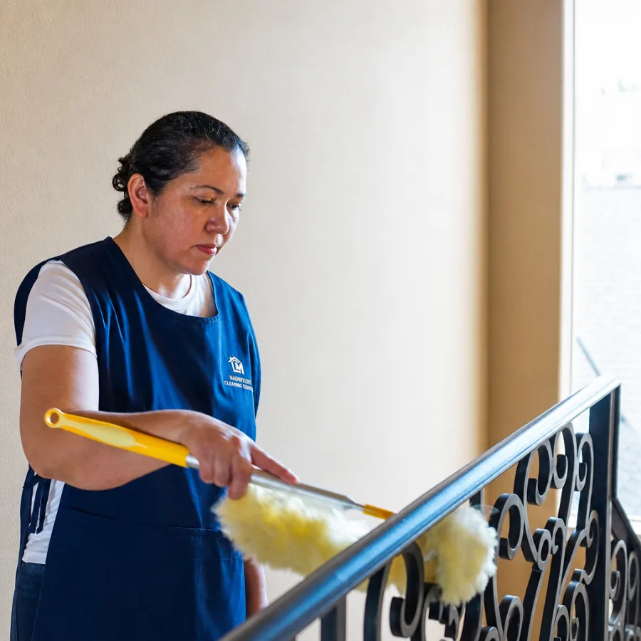 Magnificent cleaner dusting staircase railings during a home cleaning visit